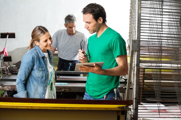 Vorgesetzter hält digitales Tablet in der Hand, während er Arbeiter anschaut — Stockfoto