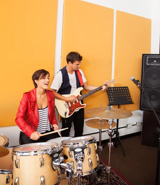 Жінка барабанщик і чоловік гітарист виступає в студії — стокове фото