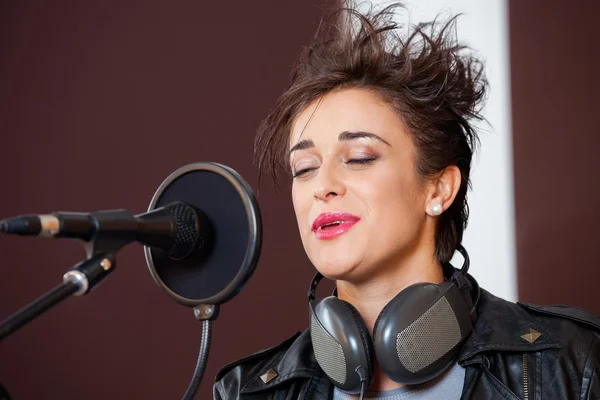 Mujer con los ojos cerrados cantando en el estudio de grabación — Foto de Stock