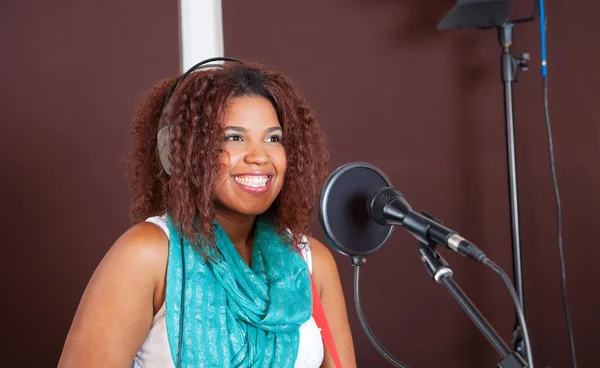 Cantora feminina sorrindo enquanto se apresenta no estúdio — Fotografia de Stock