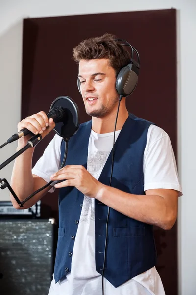 Hombre cantando mientras sostiene el micrófono en el estudio —  Fotos de Stock