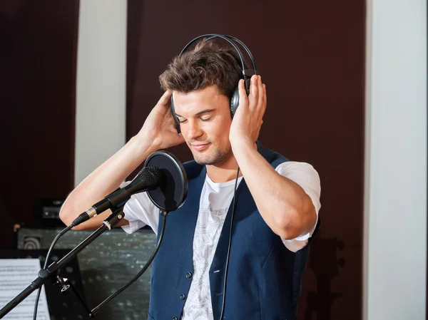 Erkek şarkıcı dikkatle kulaklık aracılığıyla müzik dinlemek — Stok fotoğraf