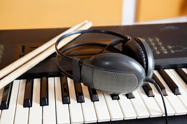 Auriculares y palos de batería en el piano — Foto de Stock