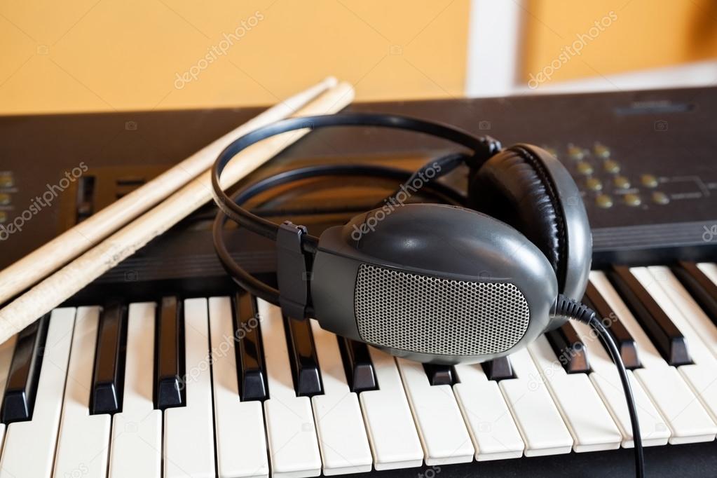 Headphones And Drumsticks On Piano