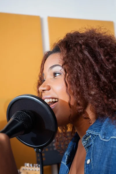 Jovem mulher cantando em estúdio de gravação — Fotografia de Stock