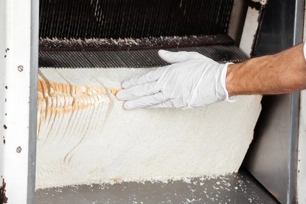 Panettieri mano toccando pane in affettatrice — Foto Stock