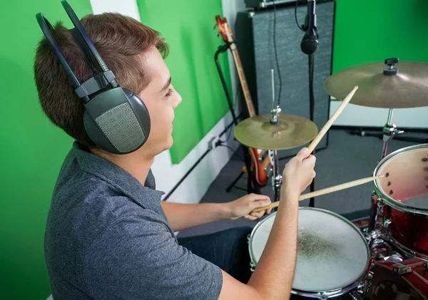 Baterista usando fones de ouvido enquanto realizando em estúdio de gravação — Fotografia de Stock