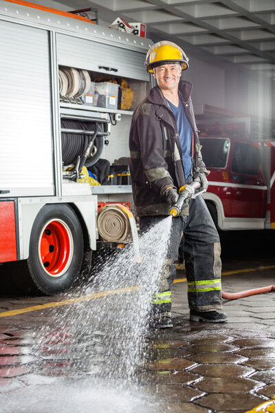 Confident Fireman Spraying Water During Practice