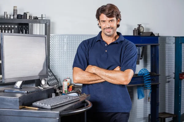 Mecánico sonriente de pie brazos cruzados en taller de reparación —  Fotos de Stock