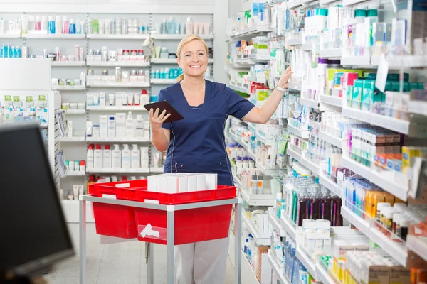 Joyeuse femme pharmacien mise à jour stock en tablette numérique — Photo