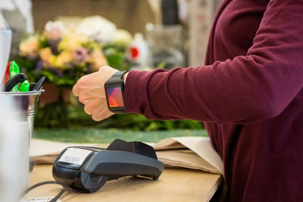 Cliente pagando a través de reloj inteligente en la tienda de flores — Foto de Stock