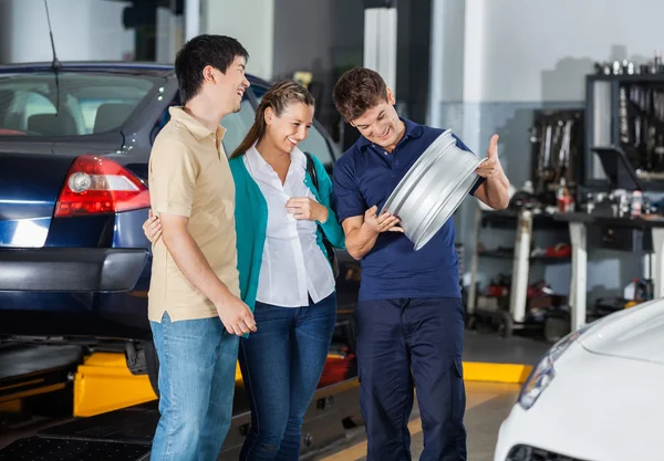 Técnico y pareja mirando a Hubcap — Foto de Stock