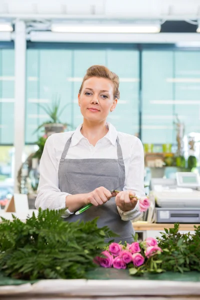 Florista segura cortando el tallo en Rose en la tienda de flores —  Fotos de Stock