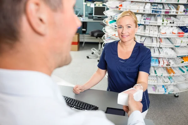 Chimiste mature donnant la médecine au client en pharmacie — Photo