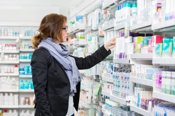 Vrouwelijke koper kiezen Product bij apotheek — Stockfoto