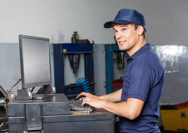 Nachdenklicher Mechaniker mit Computer in der Werkstatt — Stockfoto
