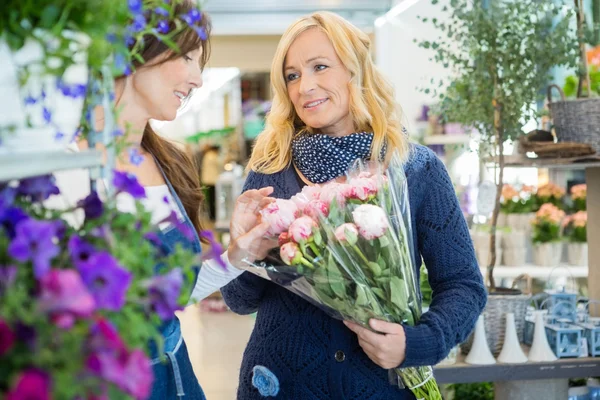 Флорист помогает клиенту в покупке цветочного букета в магазине — стоковое фото