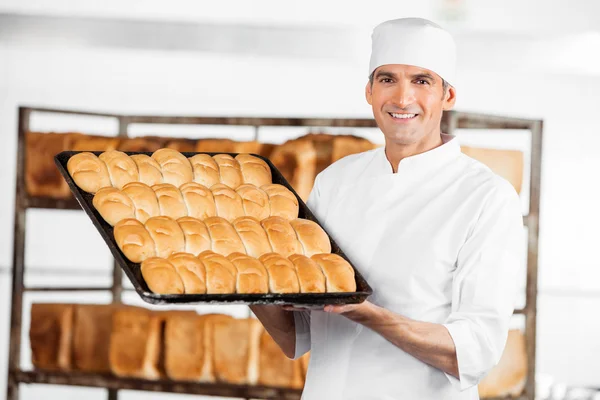 Mature boulanger montrant des pains dans la plaque de cuisson — Photo