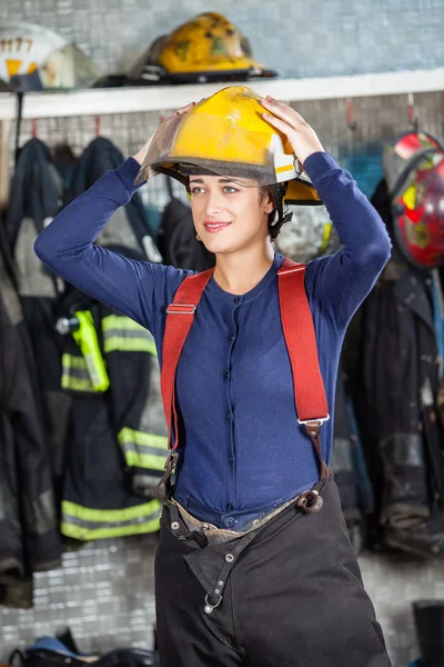 Mulher de fogo sorrindo usando capacete no quartel de bombeiros — Fotografia de Stock
