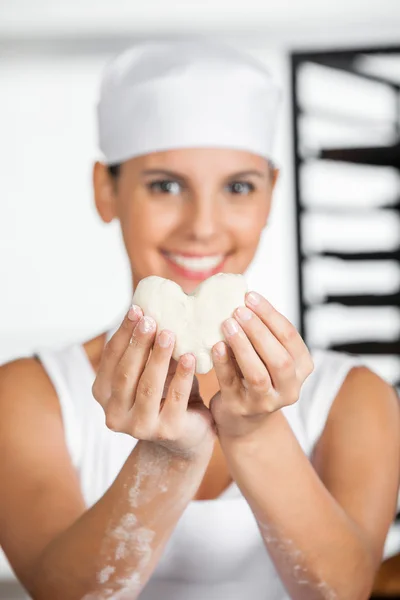 Baker feminino segurando forma do coração massa — Fotografia de Stock