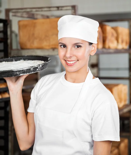 Mujer Baker sonriendo mientras lleva bandeja de masa — Foto de Stock