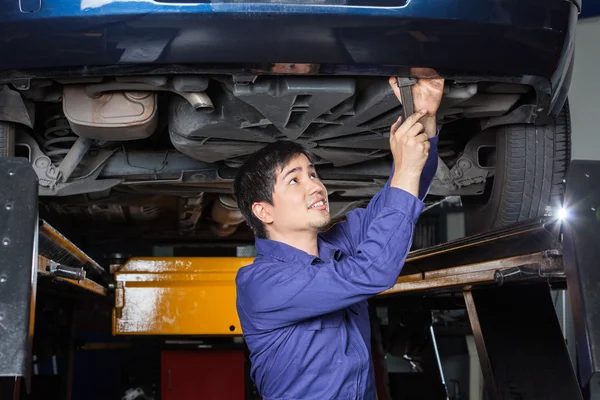 Mechaniker mit Schraubenschlüssel unter angehobenem Auto — Stockfoto