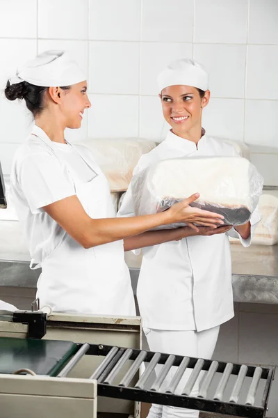 Bäcker schauen sich beim Packen von Broten an — Stockfoto