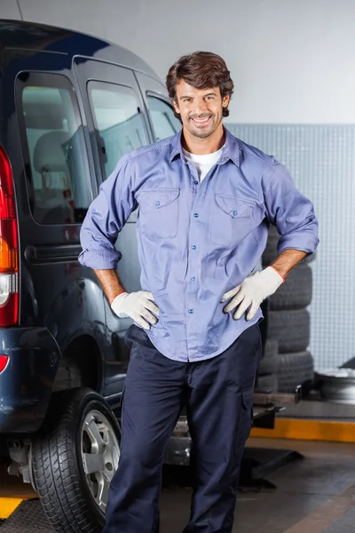 Mechanic permanent met handen op heup met de auto — Stockfoto