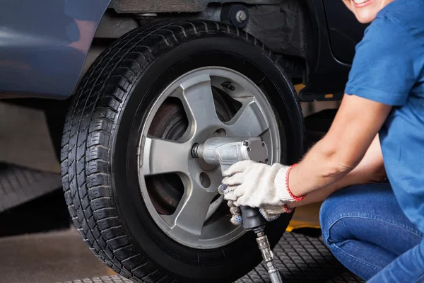 Mecánica femenina usando llave neumática para fijar neumático del coche — Foto de Stock