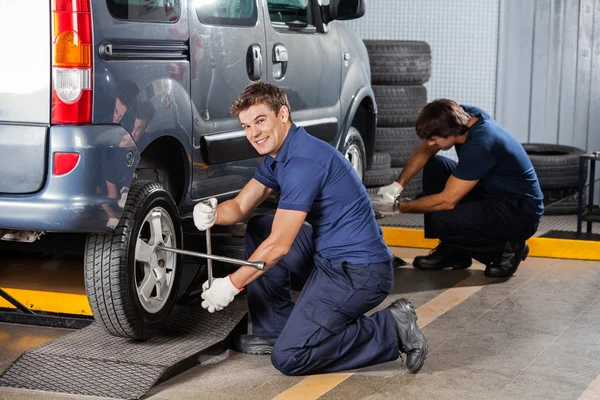 Felice meccanico riparazione auto pneumatico al negozio di riparazione — Foto Stock
