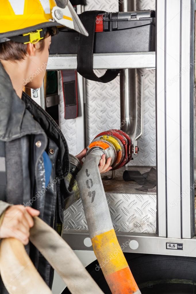 Firefighter Fixing Water Hose In Firetruck