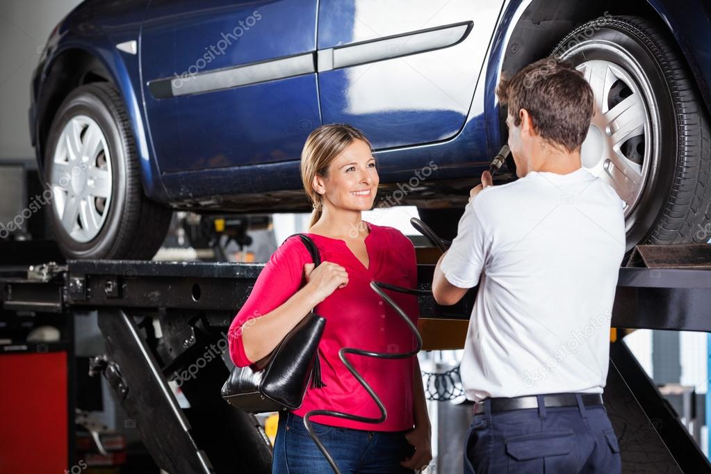 Mechanic Discussing With Customer While Filling Car Tire