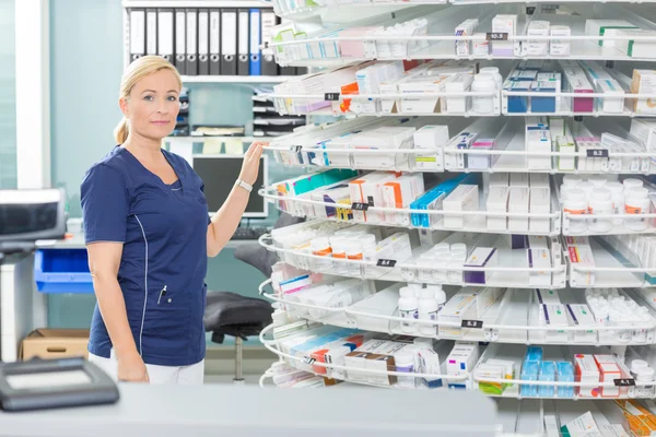 Química femenina de pie junto a los estantes en farmacia — Foto de Stock