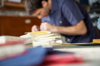 Arka planda çalışan erkeğin tabloyla kağıtlara yığılmış