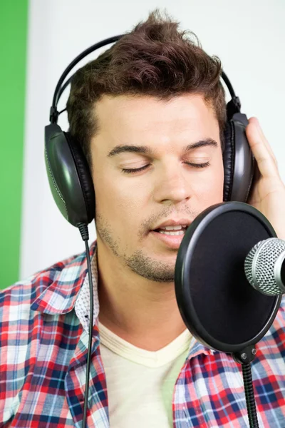 Homem com olhos fechados cantando em estúdio de gravação — Fotografia de Stock