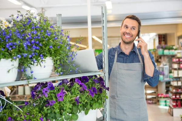 Florist med ordning på mobiltelefon i blomsteraffär — Stockfoto