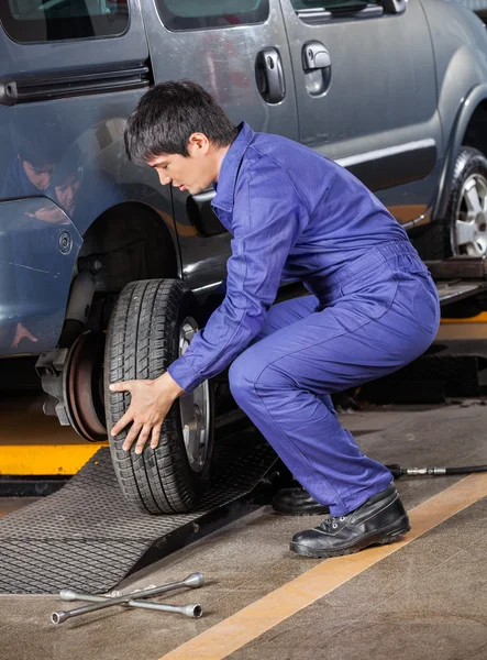 Meccanico che cambia pneumatico dell'automobile al negozio di riparazione — Foto Stock