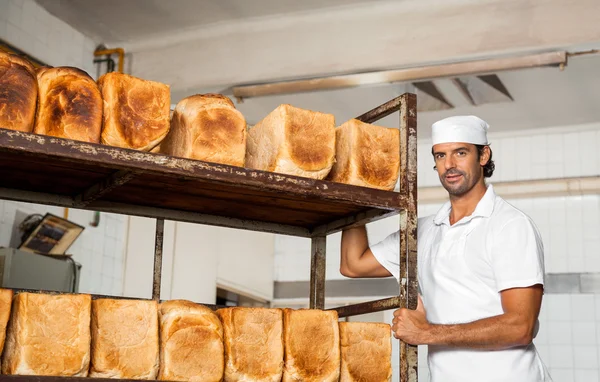 Mitten av vuxna manliga bagare står vid bröd Rack — Stockfoto