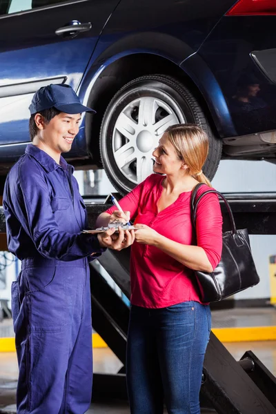 Klant Mechanic kijken terwijl de ondertekening van Document — Stockfoto