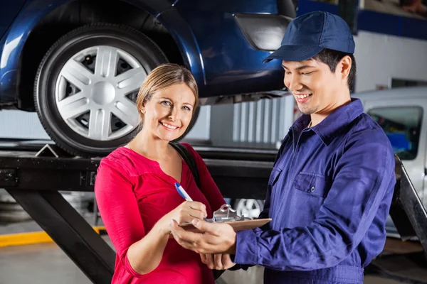 Documento di firma del cliente con meccanico in garage — Foto Stock