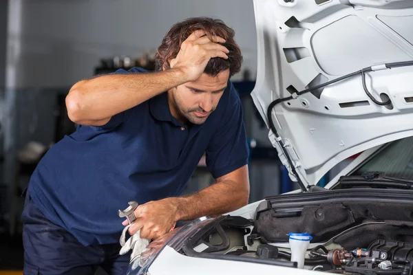 Mécanicien examinant moteur de voiture à l'atelier de réparation — Photo