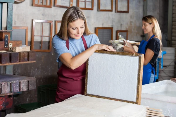 Arbeiter betrachtet getrocknetes Papier auf Schimmel in Fabrik — Stockfoto