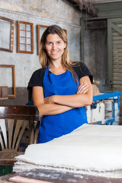 Lavoratrice con le braccia incrociate in piedi in una fabbrica di carta — Foto Stock