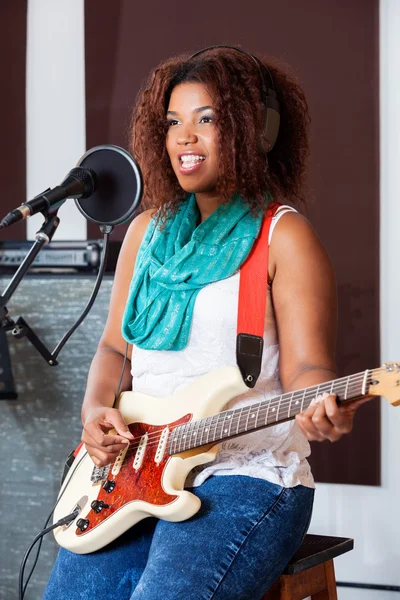 Cantora feminina tocando guitarra elétrica enquanto olha para longe — Fotografia de Stock