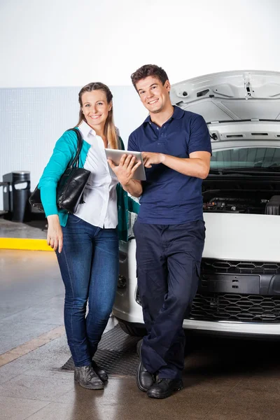 Zufriedener Kunde und Mechaniker mit digitalem Tablet in der Garage — Stockfoto