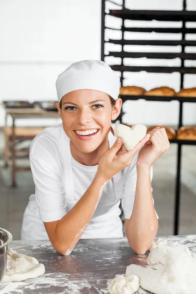 Baker Holding Heart Shape Dough While Leaning On Table — Stock Photo, Image