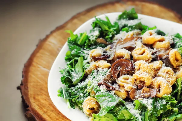 Mushroom tortellini with Parmesan cheese and arugula (shallow dof) — Stock Photo, Image