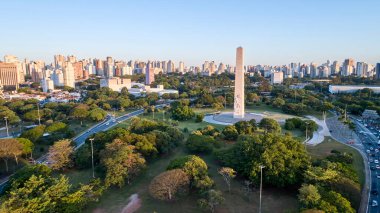 Ibirapuera Parkı 'nın yanındaki Sao Paulo şehri ve dikilitaş anıtının havadan görünüşü. Brezilya 'nın Sao Paulo şehrinde ağaçlar ve Ibirapuera parkının yeşil alanlarıyla korunma alanı..