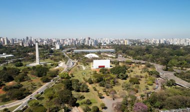 Sao Paulo şehrindeki Ibirapuera parkının havadan görünüşü, dikilitaş anıt. Ağaçları ve Ibirapuera parkının yeşil alanı olan korunma alanı. Güneşli bir günde arka planda ofis binaları ve daireler.