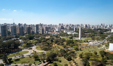 Sao Paulo şehrindeki Ibirapuera parkının havadan görünüşü, dikilitaş anıt. Ağaçları ve Ibirapuera parkının yeşil alanı olan korunma alanı. Güneşli bir günde arka planda ofis binaları ve daireler.